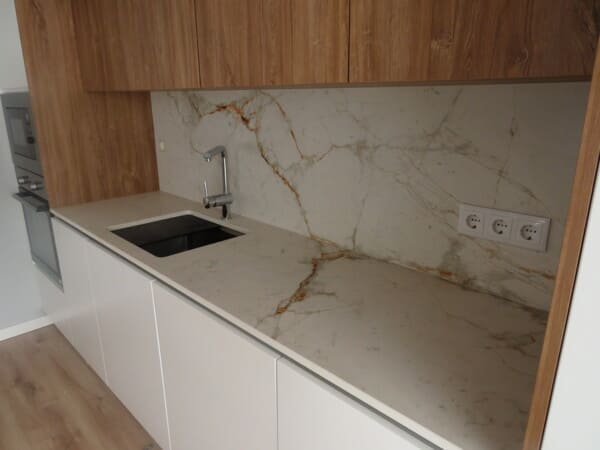 Cozinha personalizada de alto padrão com bancada e backsplash em pedra natural e móveis em nogueira