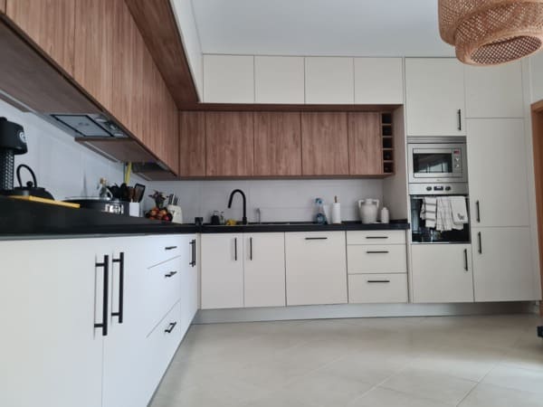 Cozinha por medida moderna em termolaminado branco mate e madeira nogueira, com móveis superiores de duas profundidades e design funcional e inovador