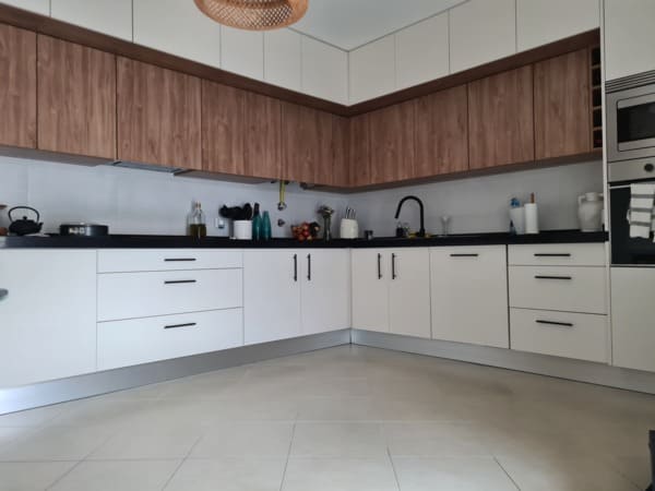 Móveis de cozinha por medida em branco mate e madeira nogueira, com armários superiores em dois níveis de profundidade